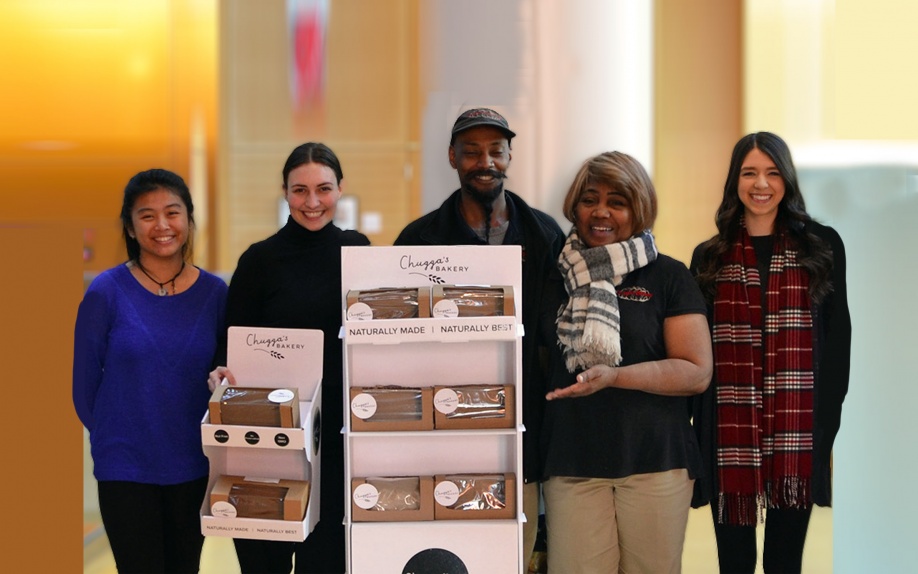 Chuggas bakery owners with DNEP students standing next to product display
