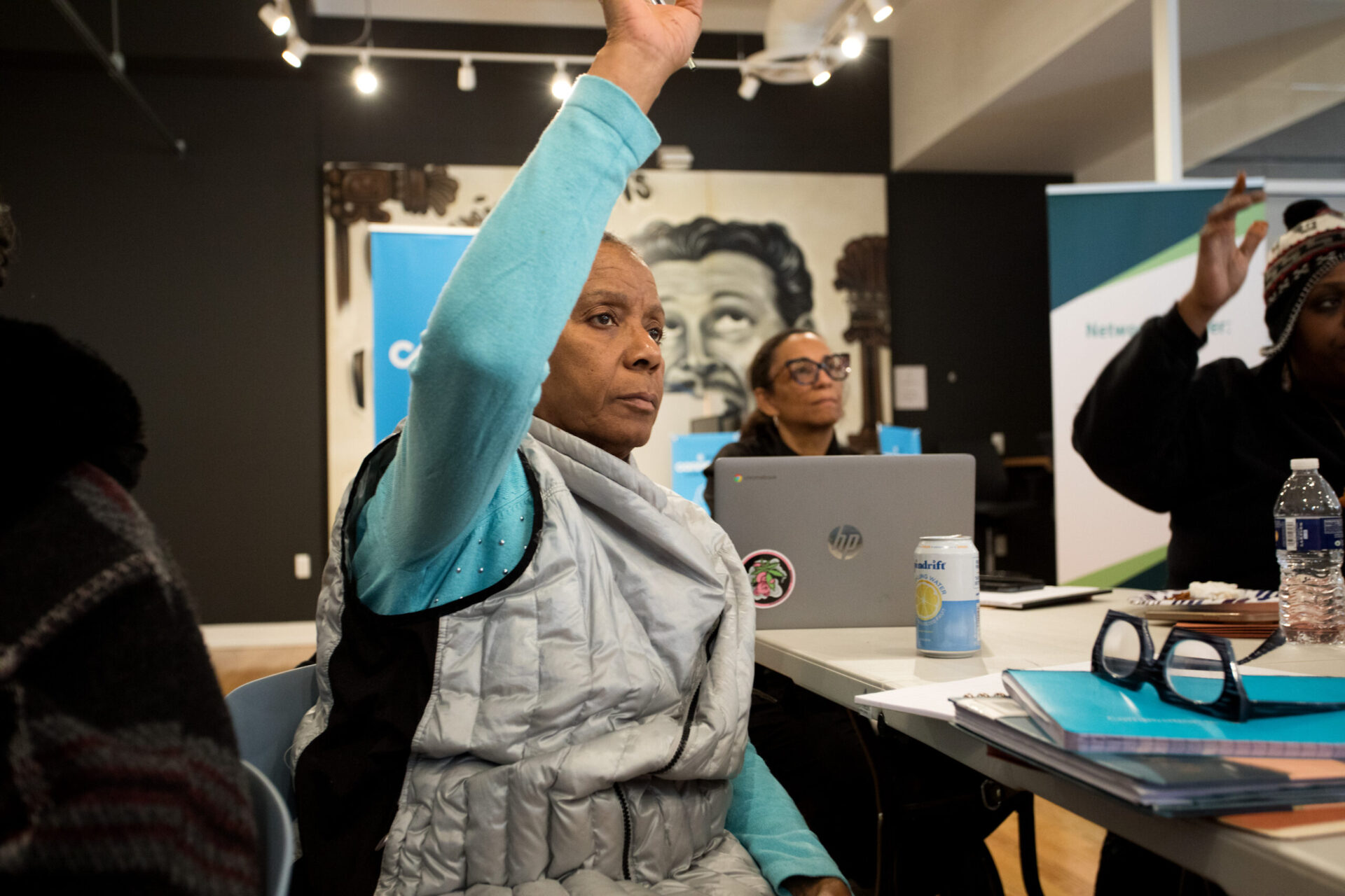 workshop participant raises hand to ask question with another participant with laptop open behind her