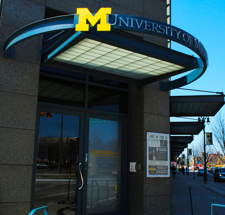 exterior of the University of Michigan detroit center Woodward Ave entrance with arched loop and block M logo