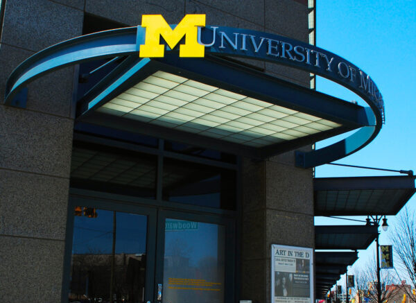 exterior of the University of Michigan detroit center Woodward Ave entrance with arched loop and block M logo