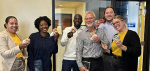 diverse group of lenders in business casual smile while holding donuts from a local bakery
