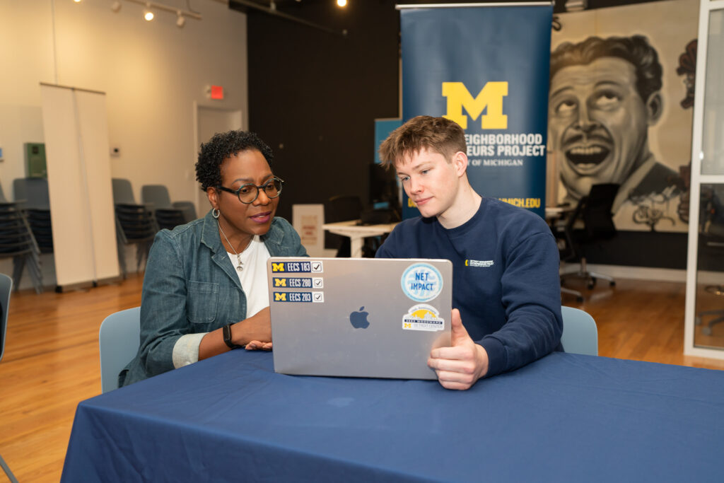 business owner and student look at a laptop together